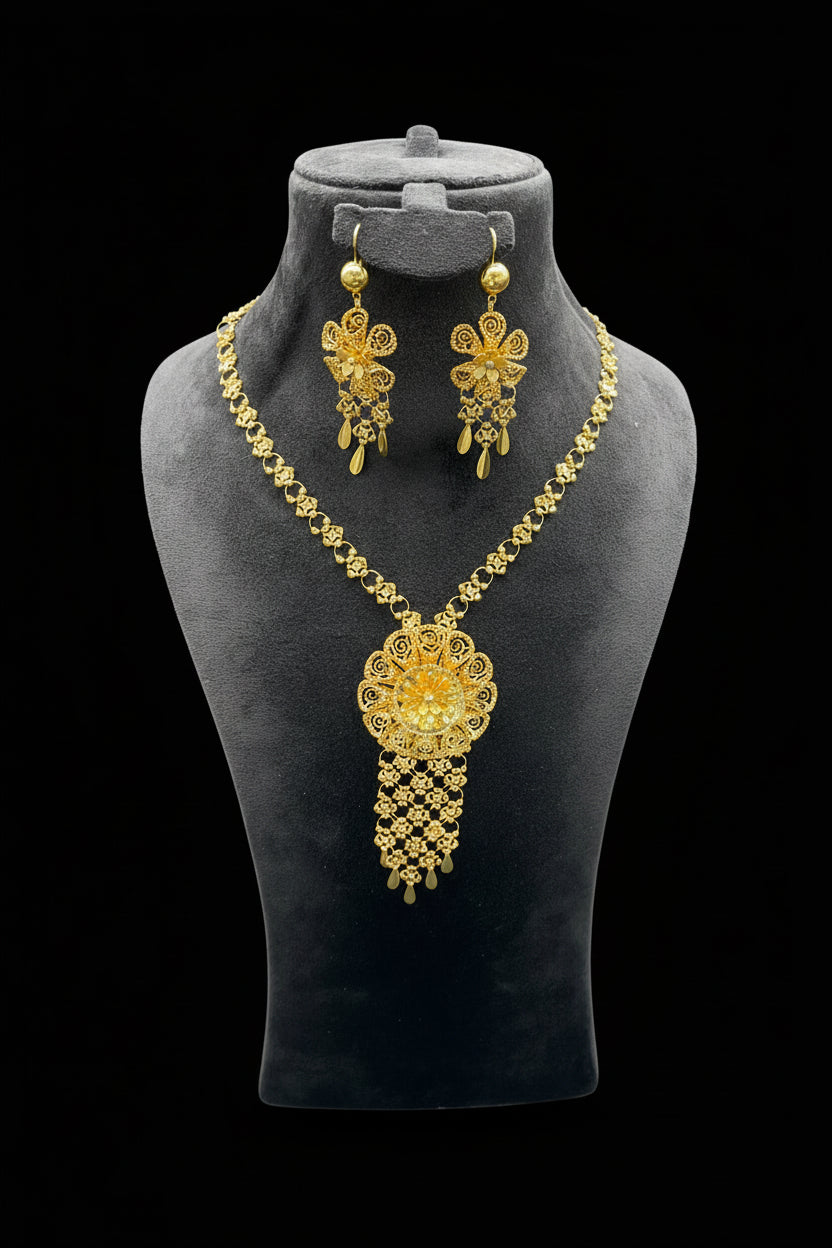 Gold necklace and earrings set on a gray mannequin bust