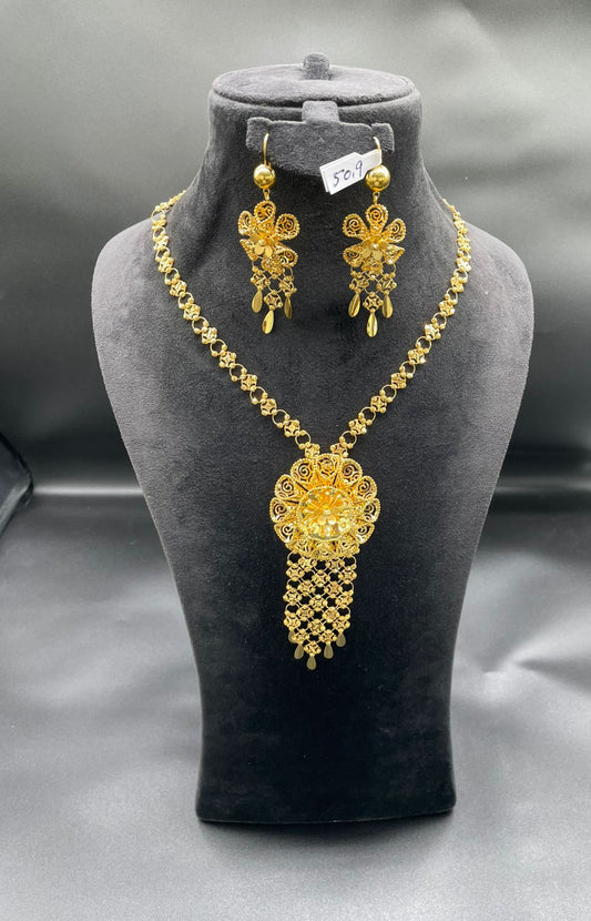 Gold necklace and earrings set on a gray mannequin bust